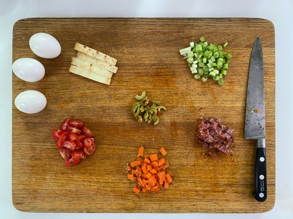 sliced carrots and green chili on brown wooden chopping board